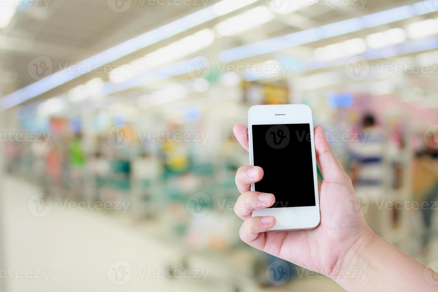 teléfono inteligente de uso manual con fondo de tienda de supermercado, mostrador de caja con cliente foto