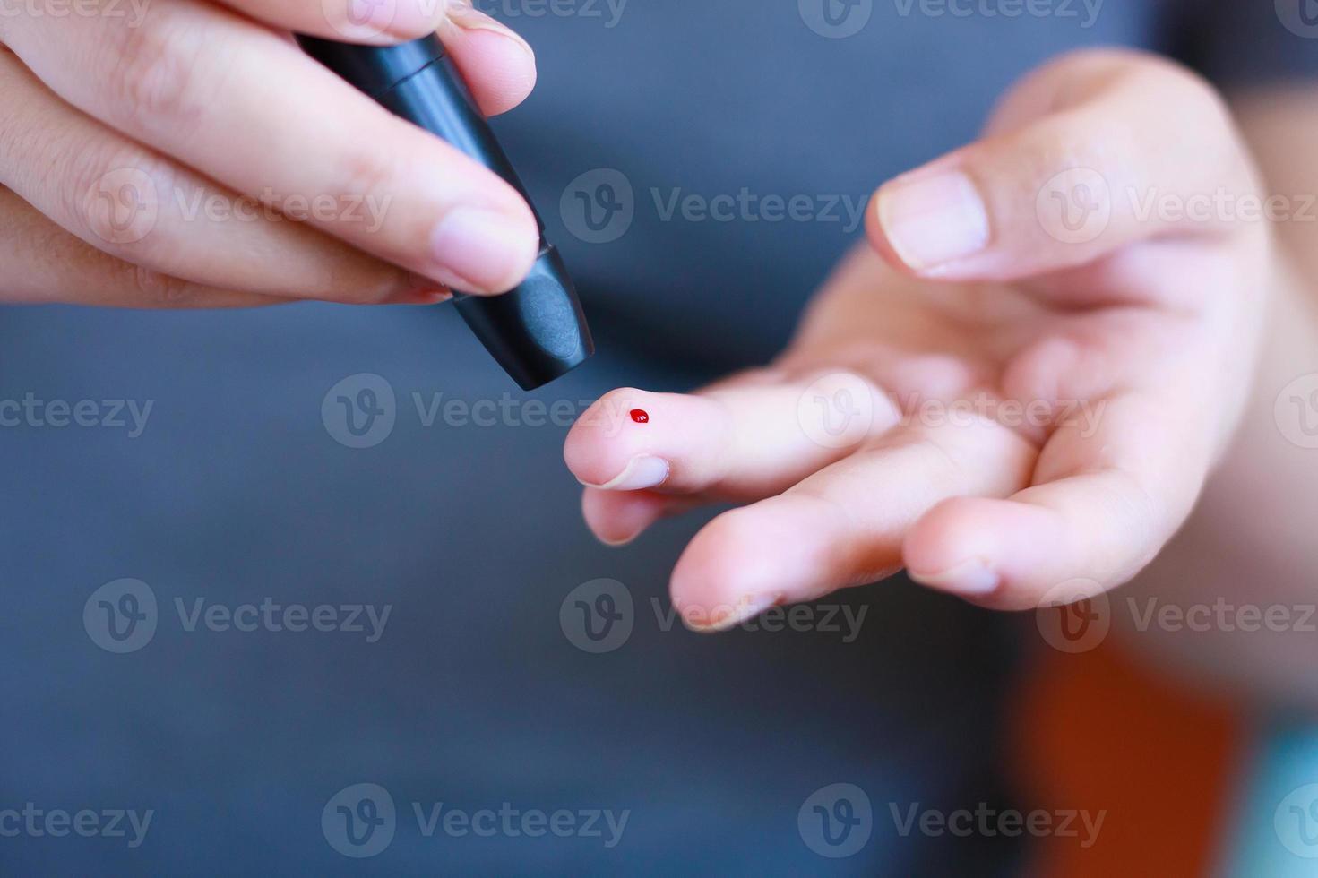 Medidor de glucosa en sangre en la mano sobre fondo azul.