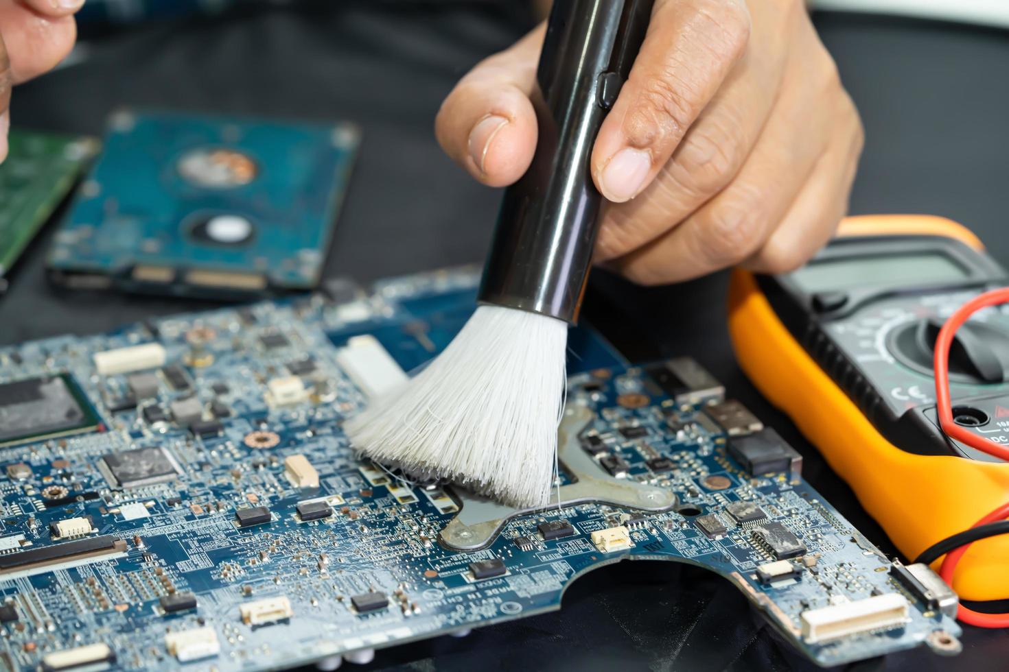 El técnico usa un cepillo y una bola de aire para limpiar el polvo en la placa de circuito de la computadora. reparación de tecnología de actualización y mantenimiento. foto