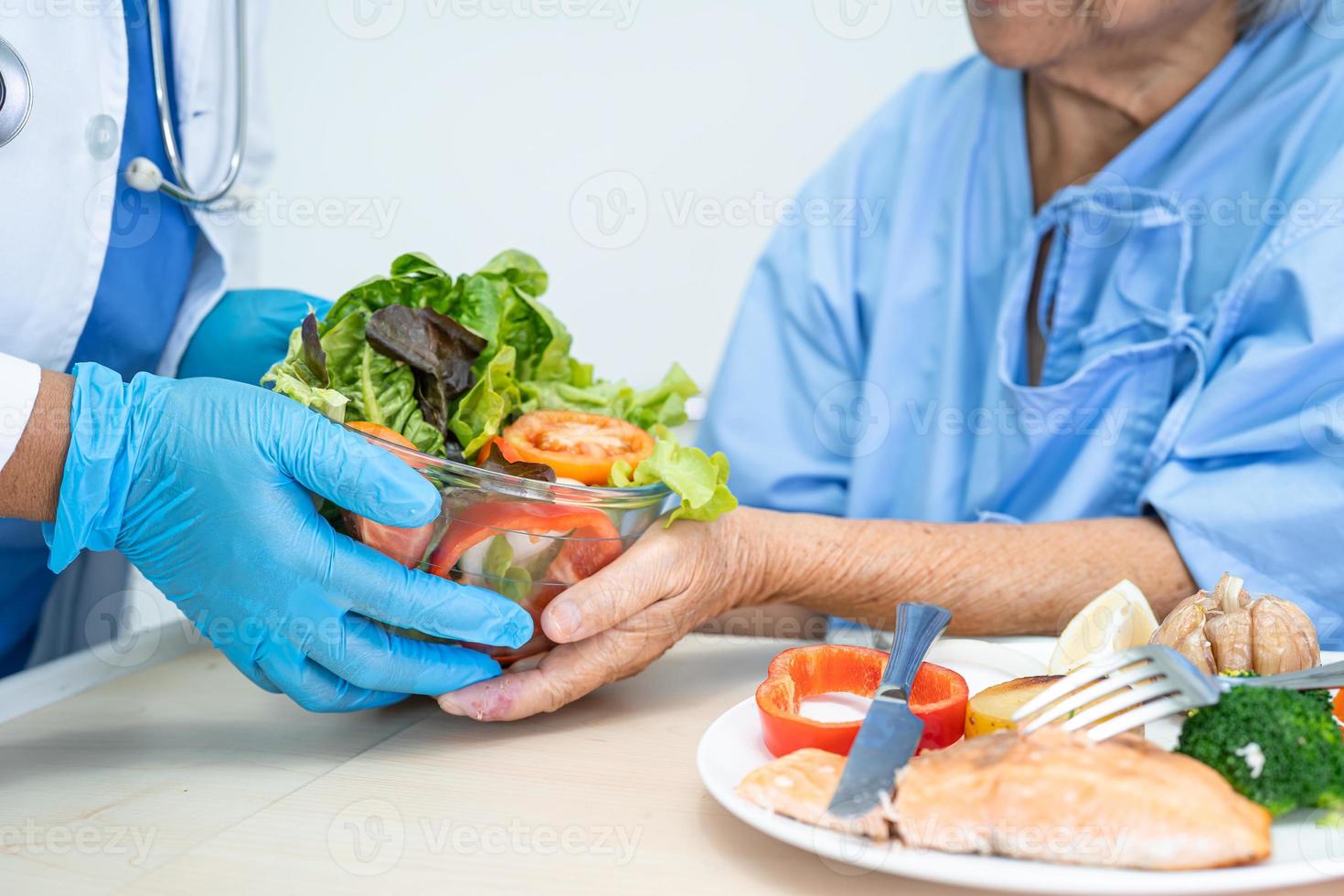 Asian senior or elderly old lady woman patient eating breakfast vegetable healthy food with hope and happy while sitting and hungry on bed in hospital. photo