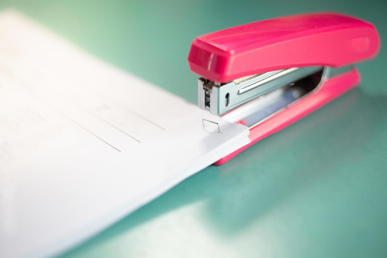 The pink stapler does not pierce through many sheets of paper.shallow focus effect. photo