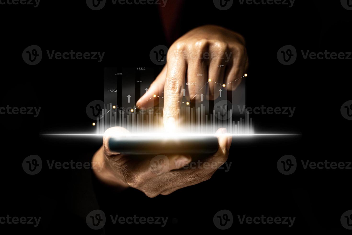 Person holding a mobile phone and pointing finger at the screen, graphic charts and fluctuations in financial data, showing business growth. Business strategy. digital business hologram. photo