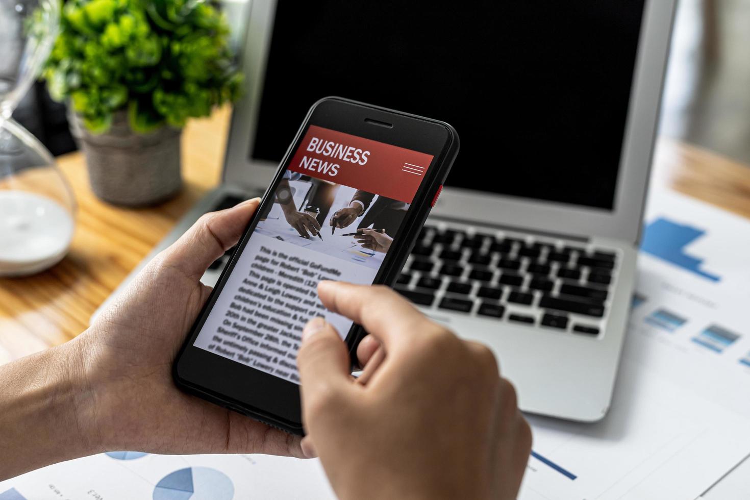 A person holding a smartphone in front of a news website, using a smartphone to read online news via the Internet network. Concept of using smartphones, entertainment media and online. photo