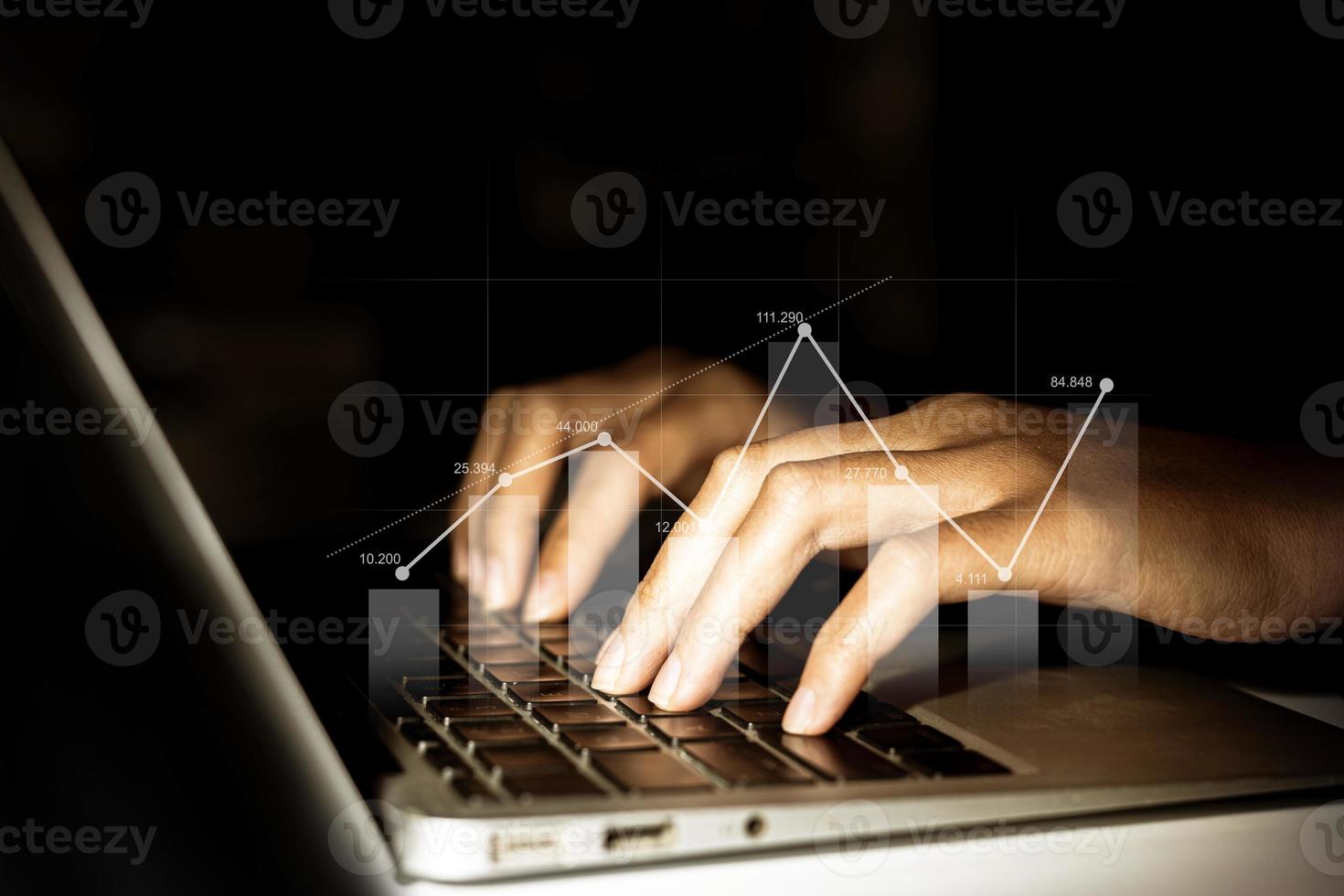 Businessman working on a laptop with a hologram of financial graphs display, a graphic showing financial and numerical growth data. The concept of financial management to grow and be profitable. photo