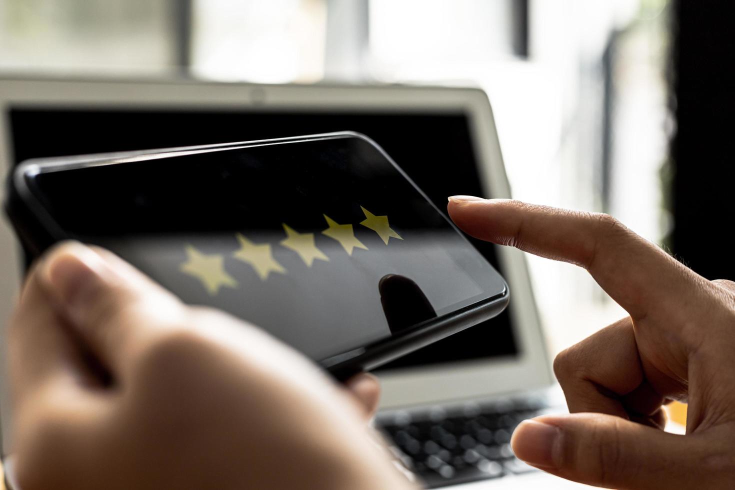 Person holding a smartphone with a screen showing 5 yellow stars, is reviewing a product through an online shopping application. Concept of using applications on smartphones via the Internet network. photo