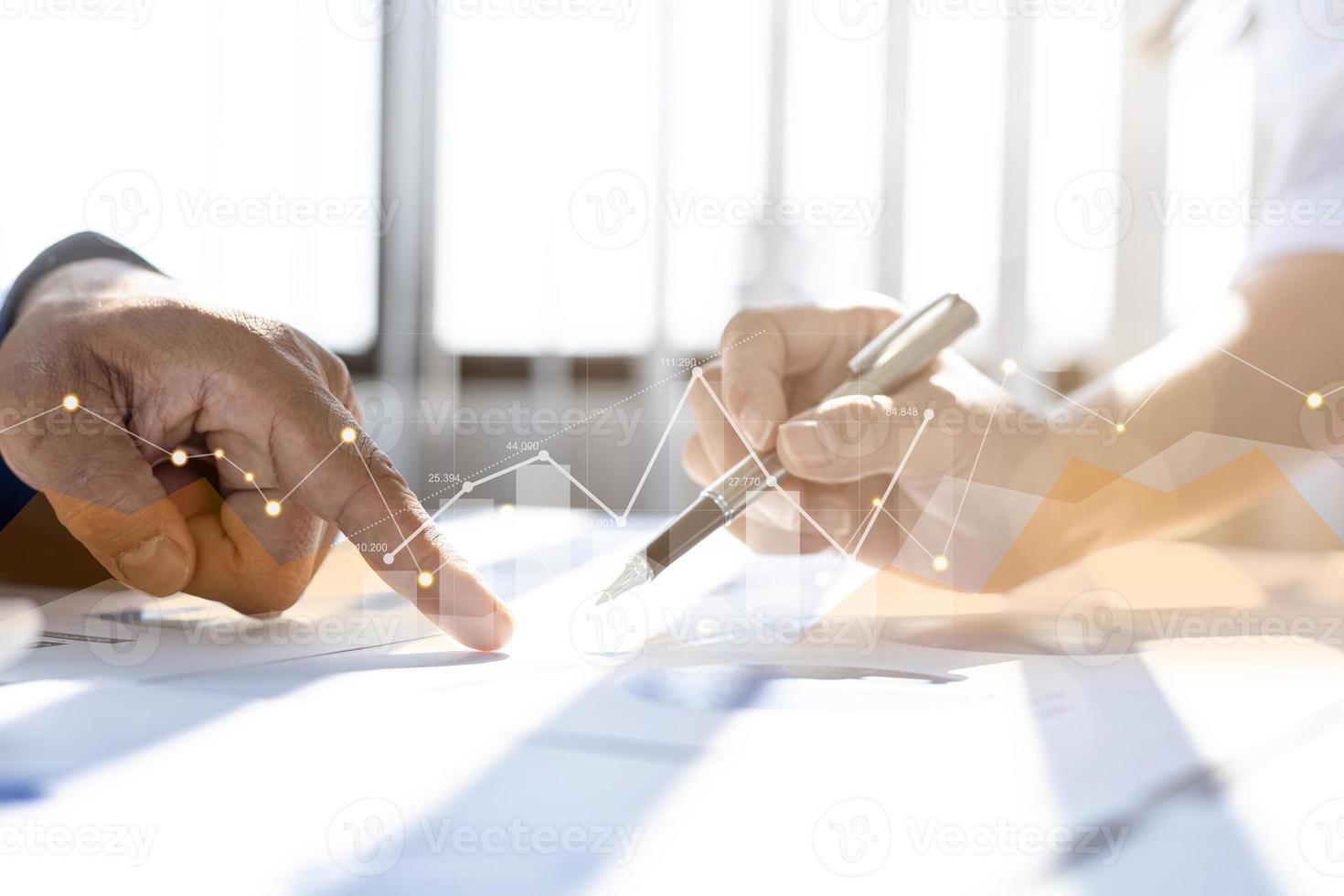Two businessmen are meeting together, they point to financial documents to discuss plans and solutions, chart graphics showing financial status and performance. Business administration concept. photo