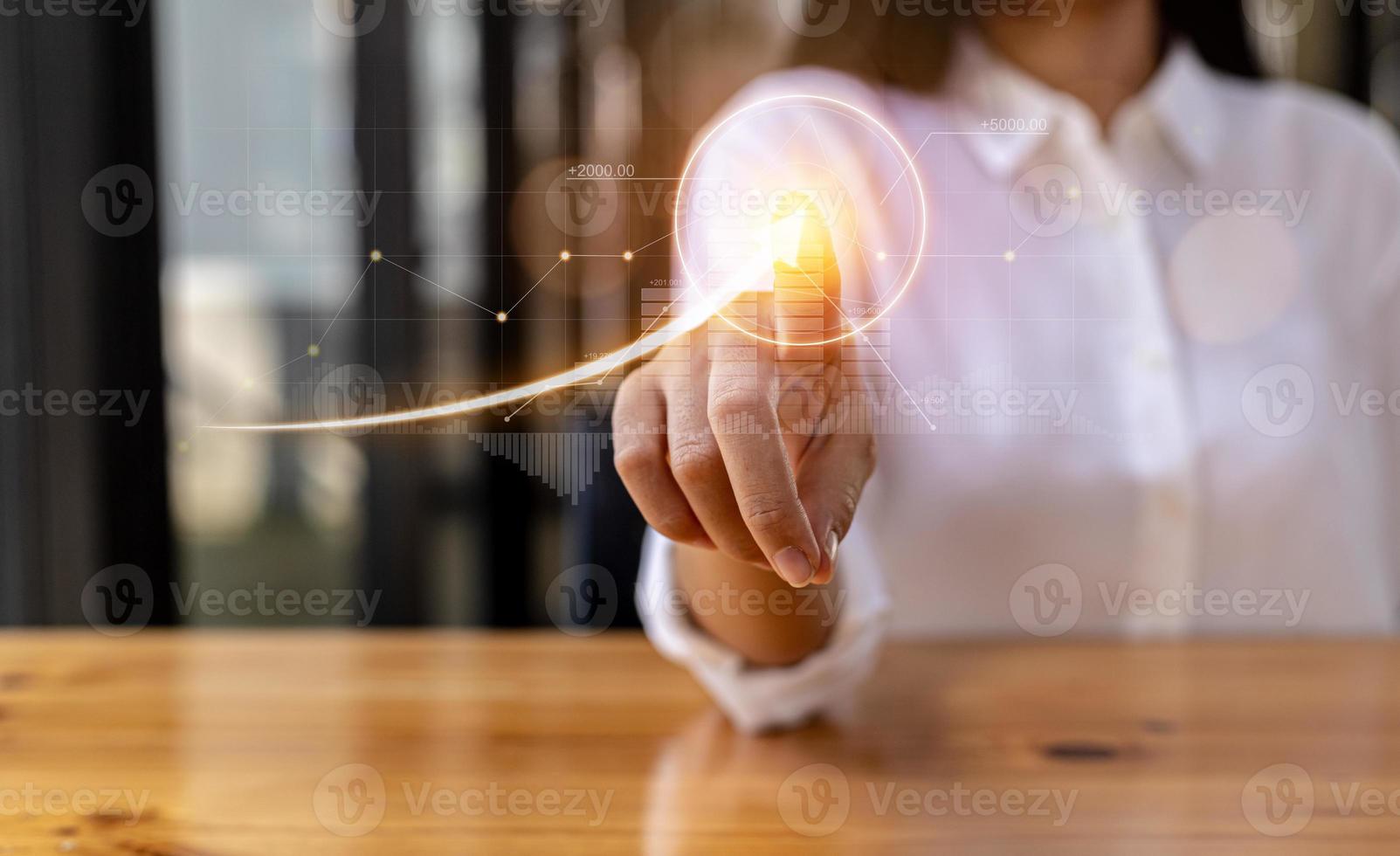 Woman pointing finger at digital financial hologram, company financial reports, graphics showing financial and numerical growth data. The concept of financial management to grow and be profitable. photo