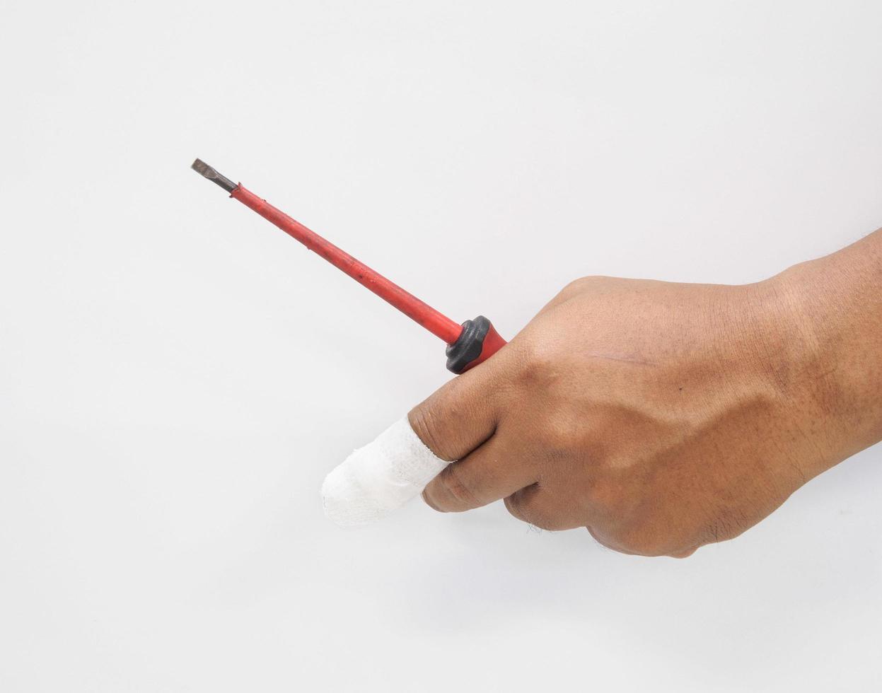 Close-up hand  Asian male technician holding a tool screwdriver in danger. And injury to the fingers from work In industrial systems With first aid With bandage at hospital on white background. photo