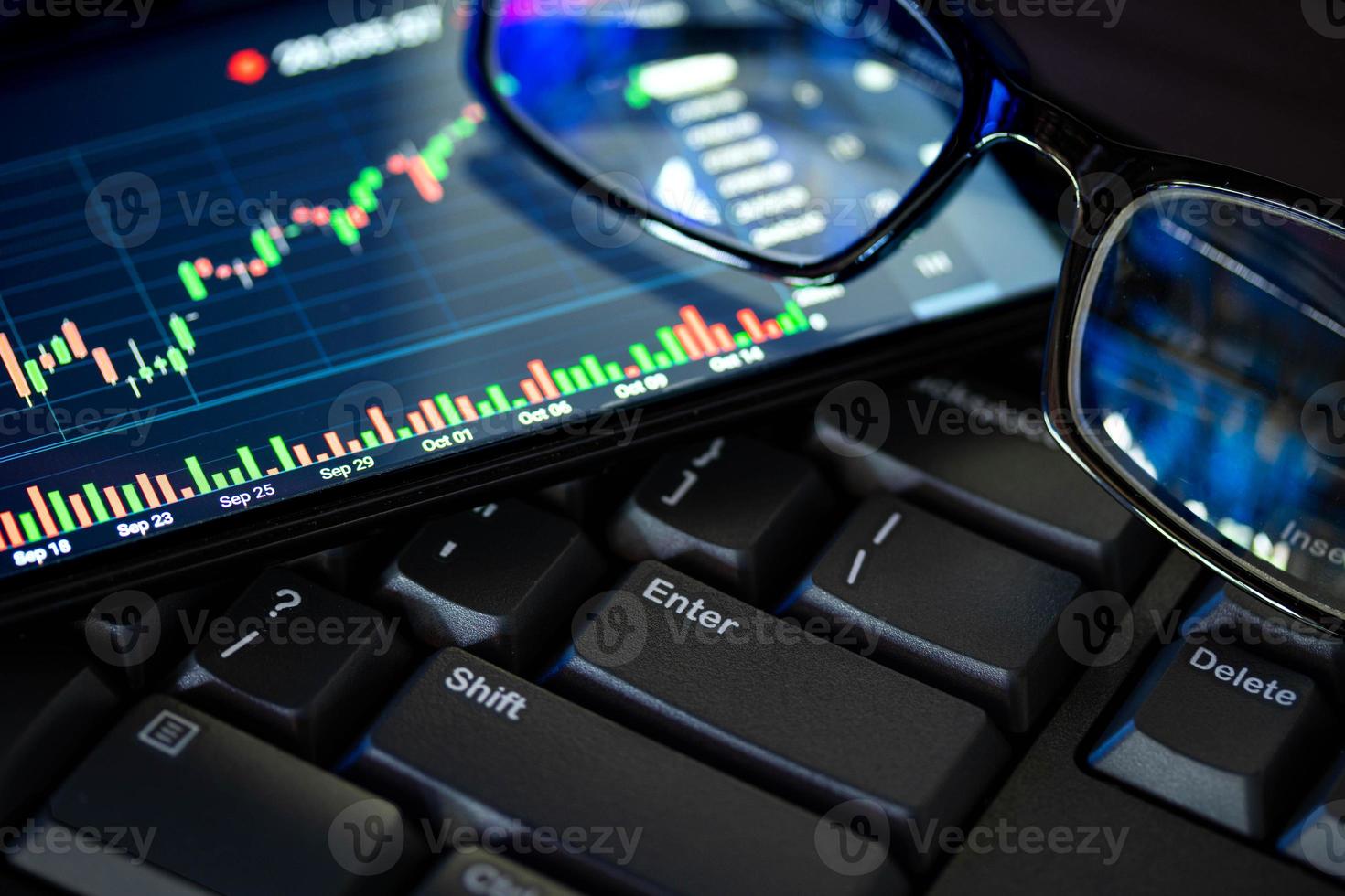 Stock market chart screen on keyboard computer and eyeglasses, online investment concept photo