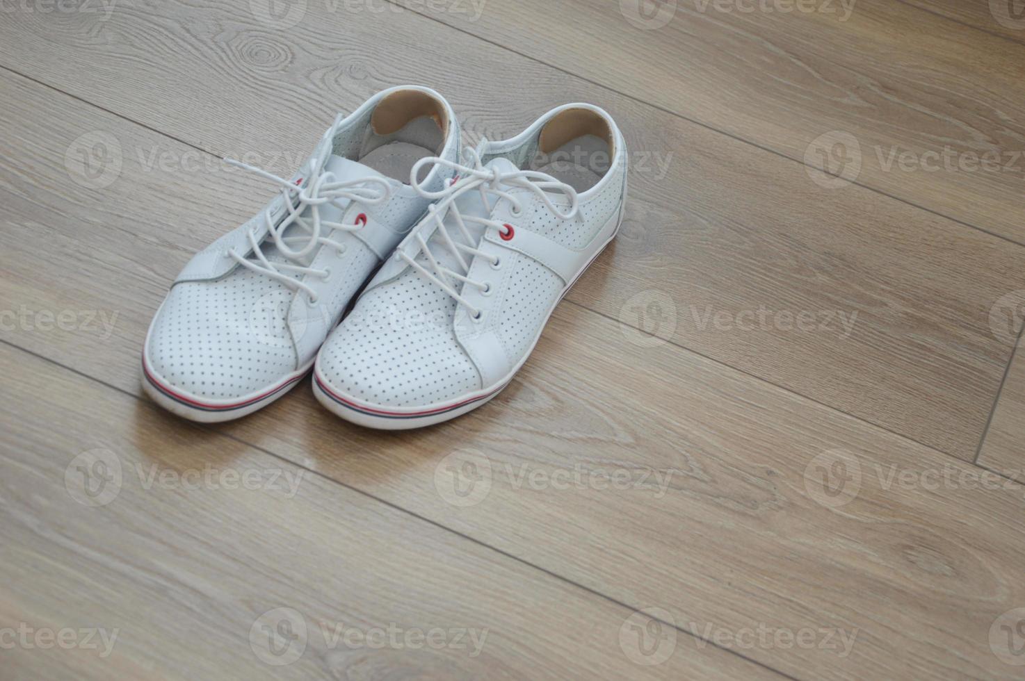A pair of stylish sports shoes on a brown wooden floor. Inserts on the back of the shoe from calluses on the heels. photo