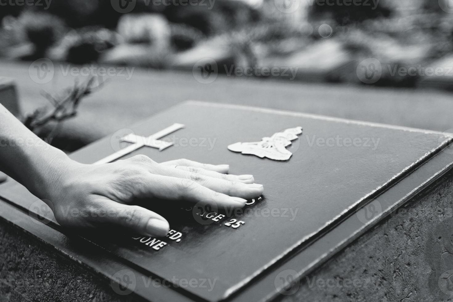 Woman's hand touching the black stone grave. Reminisce, miss, sad and lose person in the family or important people concept in black and white tone photo