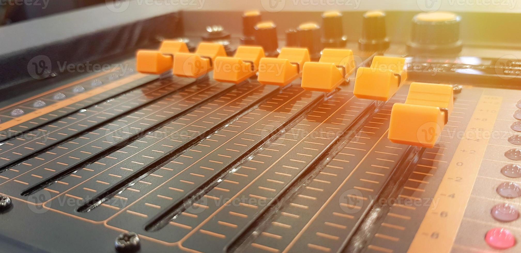 Blurred close up orange button of sound mixer panel equipment for mixing or control audio system with sunlight flare - Technology, Tool and Digital device concept photo