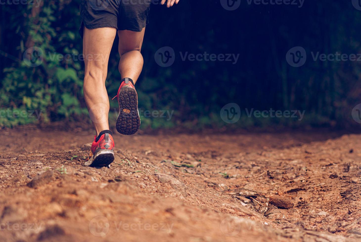 Closeup of man trail running on rocky terrain. Closeup of male feet run through rocky terrain. Focus on shoes. photo
