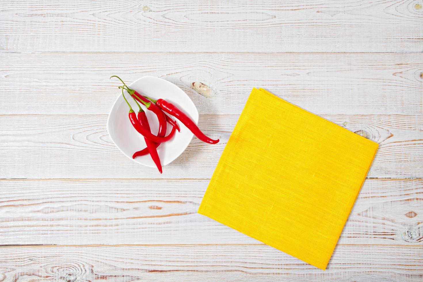 Decoration of red hot chili pepper,yellow napkin on wodden board. Set,copy space,mock up. Cayenne on white plate photo