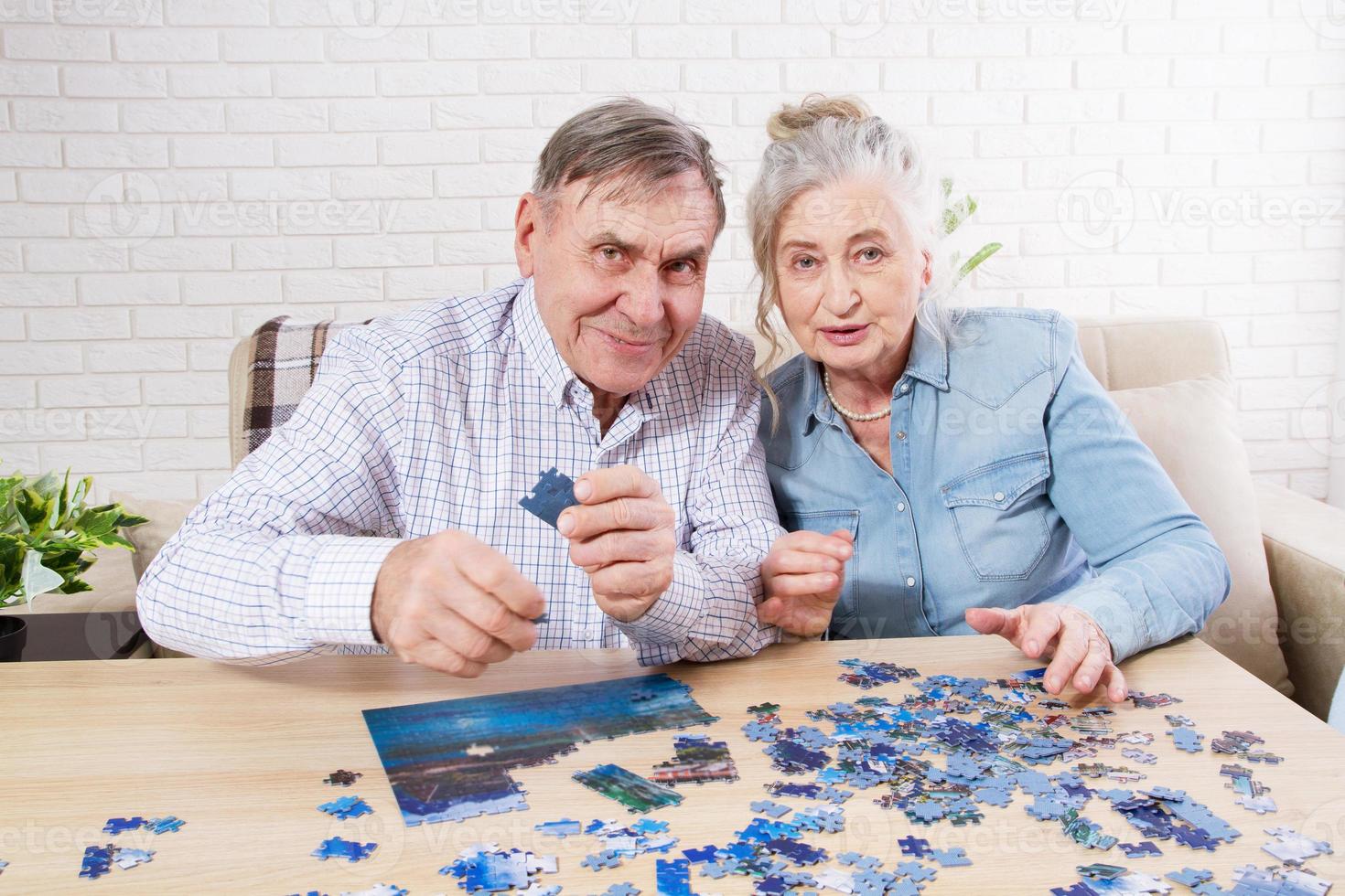 Cute Senior couple solving jigsaw puzzle together at home. photo