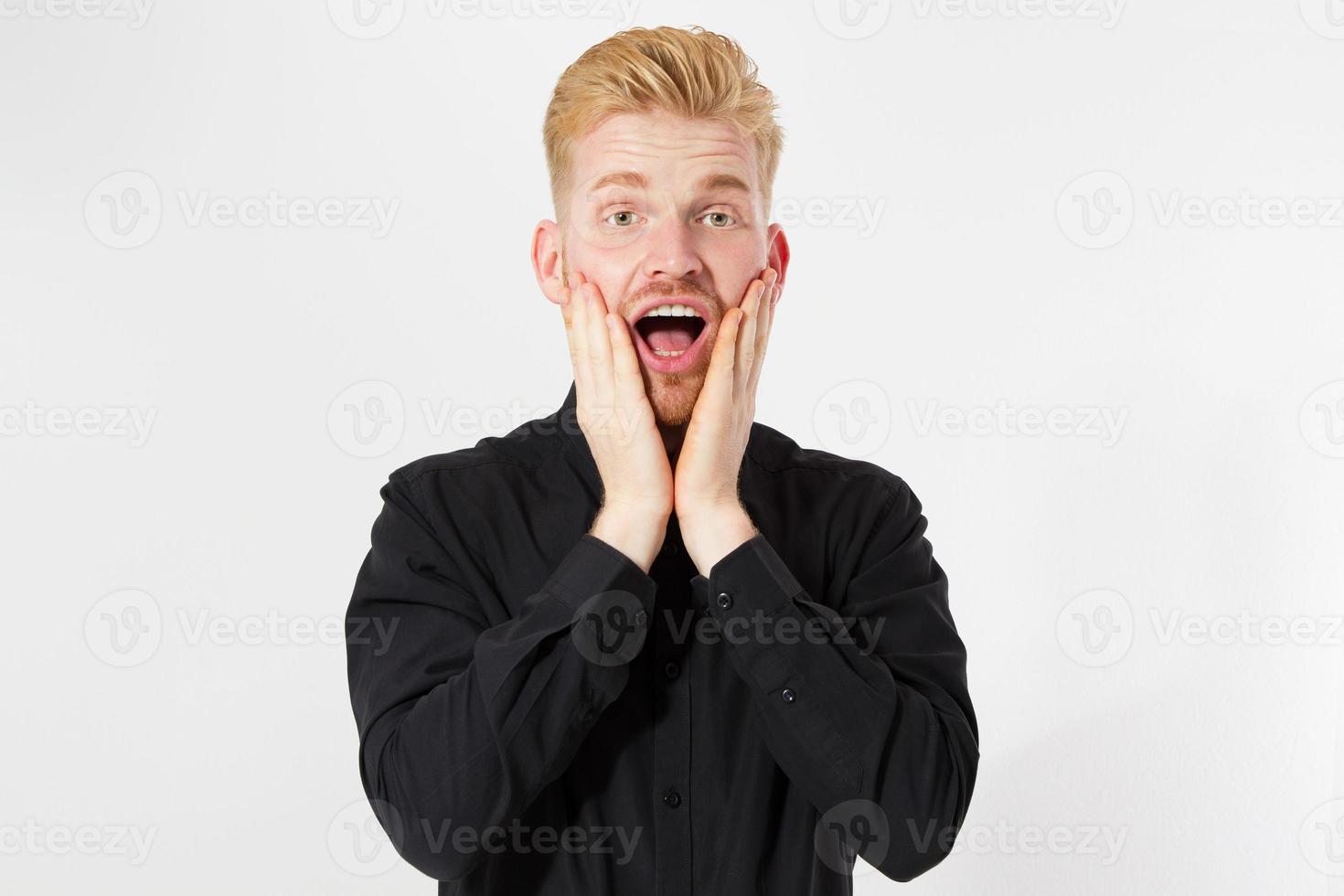 Portrait of shoked red-hair male groom realizes that he forgot to buy rings, dressed in black shirt with white bowtie, stares at camera with stupefied expression, isolated over blank copy space photo