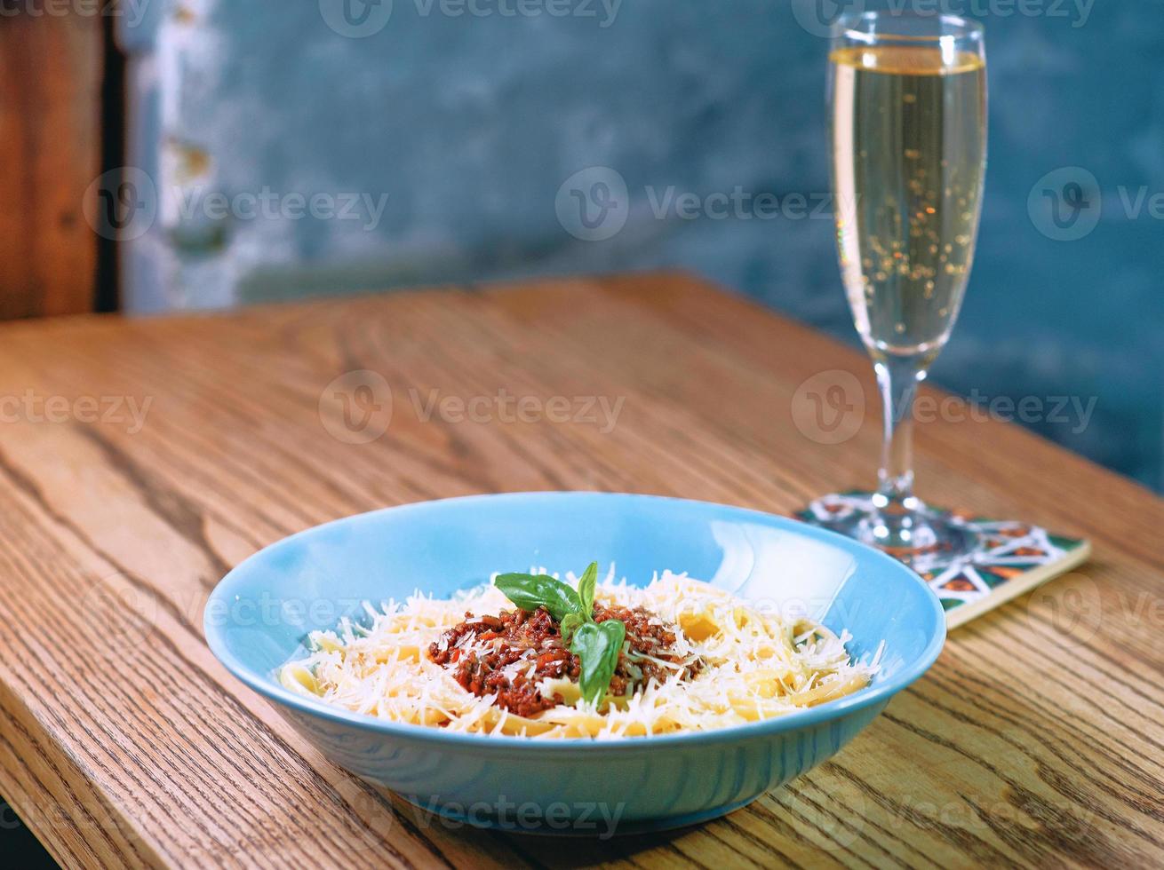 pasta bolognese in the plate and glass of sparkling dry wine on the table photo