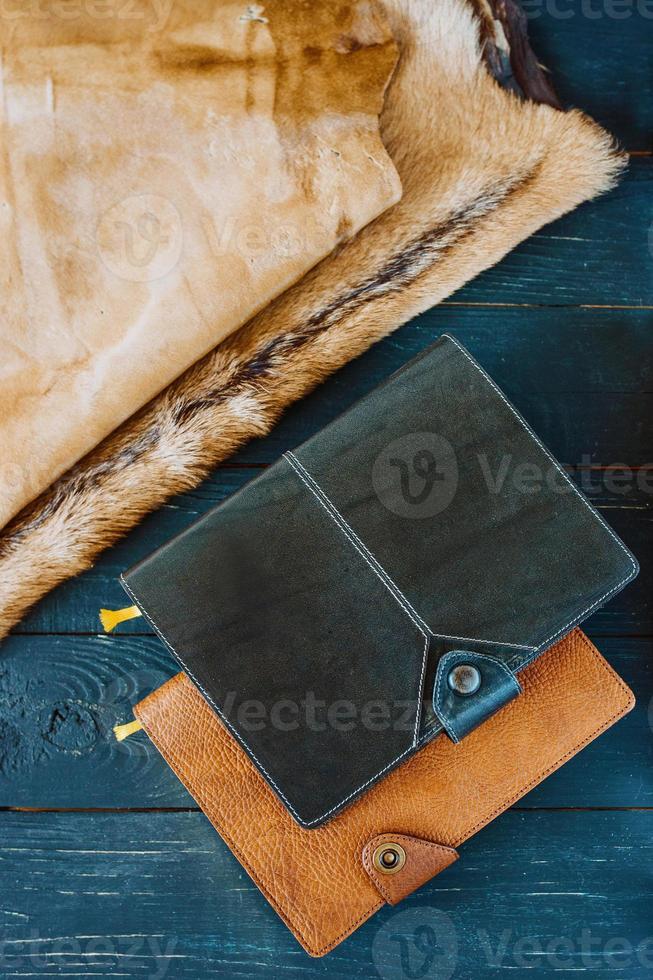 two leather handmade notebooks on dark wooden on and leather and fur background photo