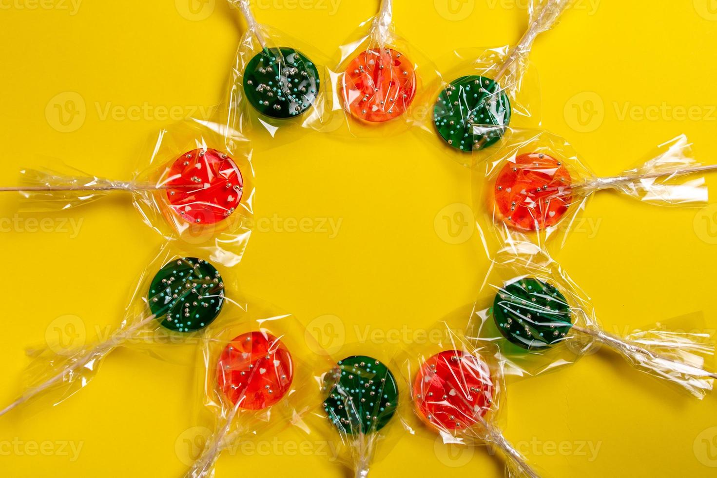 multi-colored lollipops on a stick on a yellow background photo