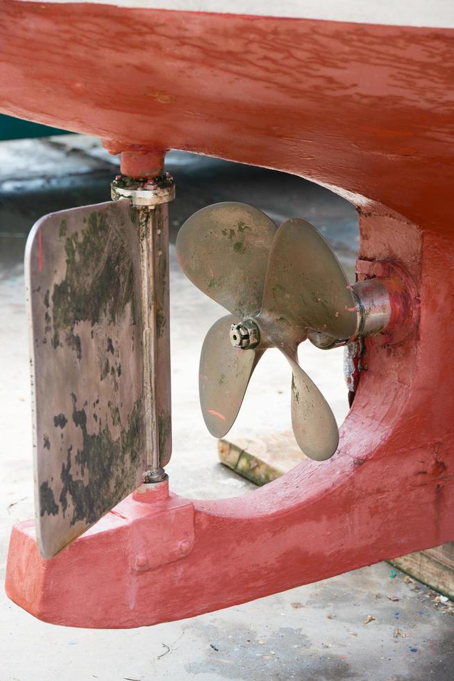 Close up of the bottom part of a red boat out of the water. Propeller and rudder. photo