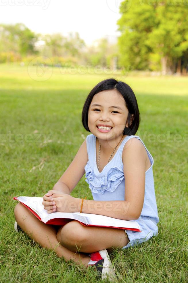 Asian little girl reading book in the park photo