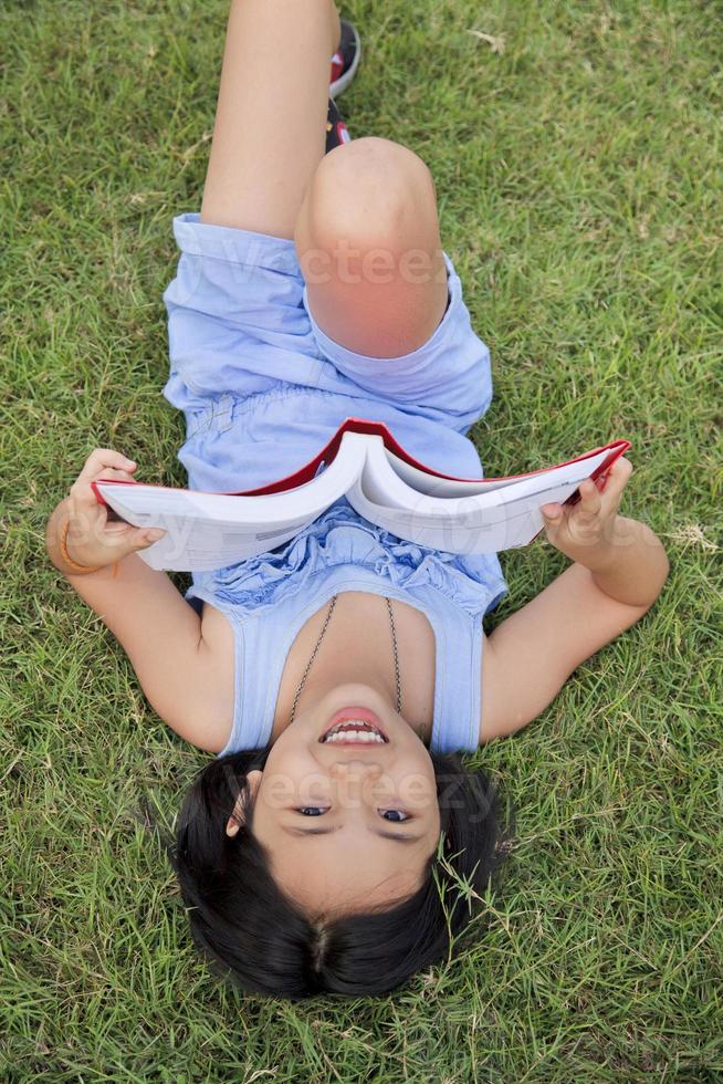 niña asiática leyendo un libro en el parque foto