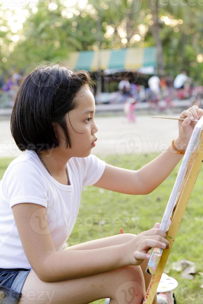 Asian little girl painting in in the park photo