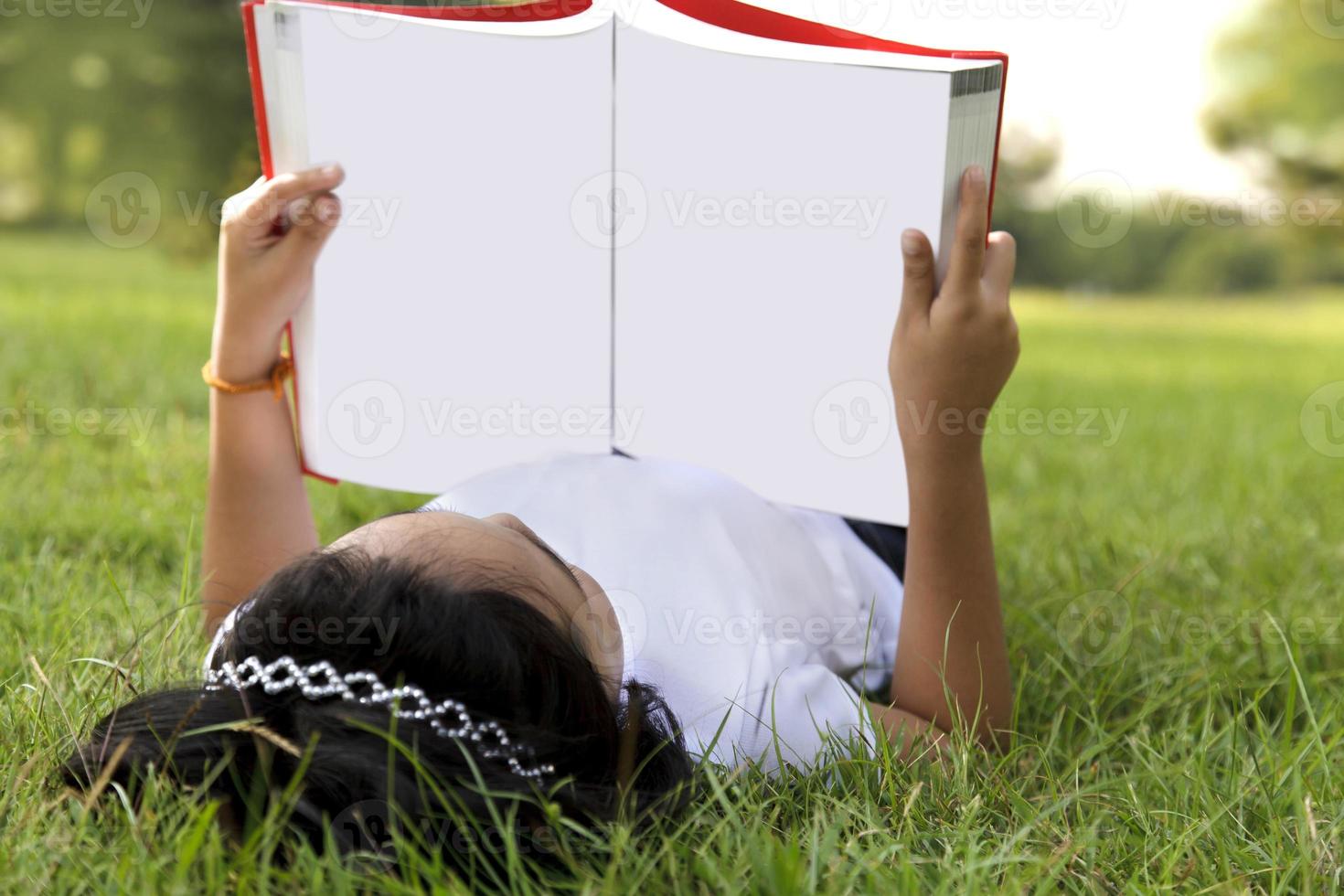 niña asiática relajarse y leer un libro en el parque foto