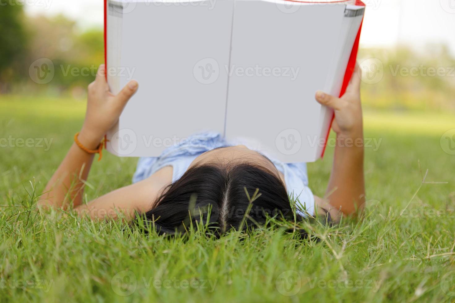 Asian little girl reading book in the park photo