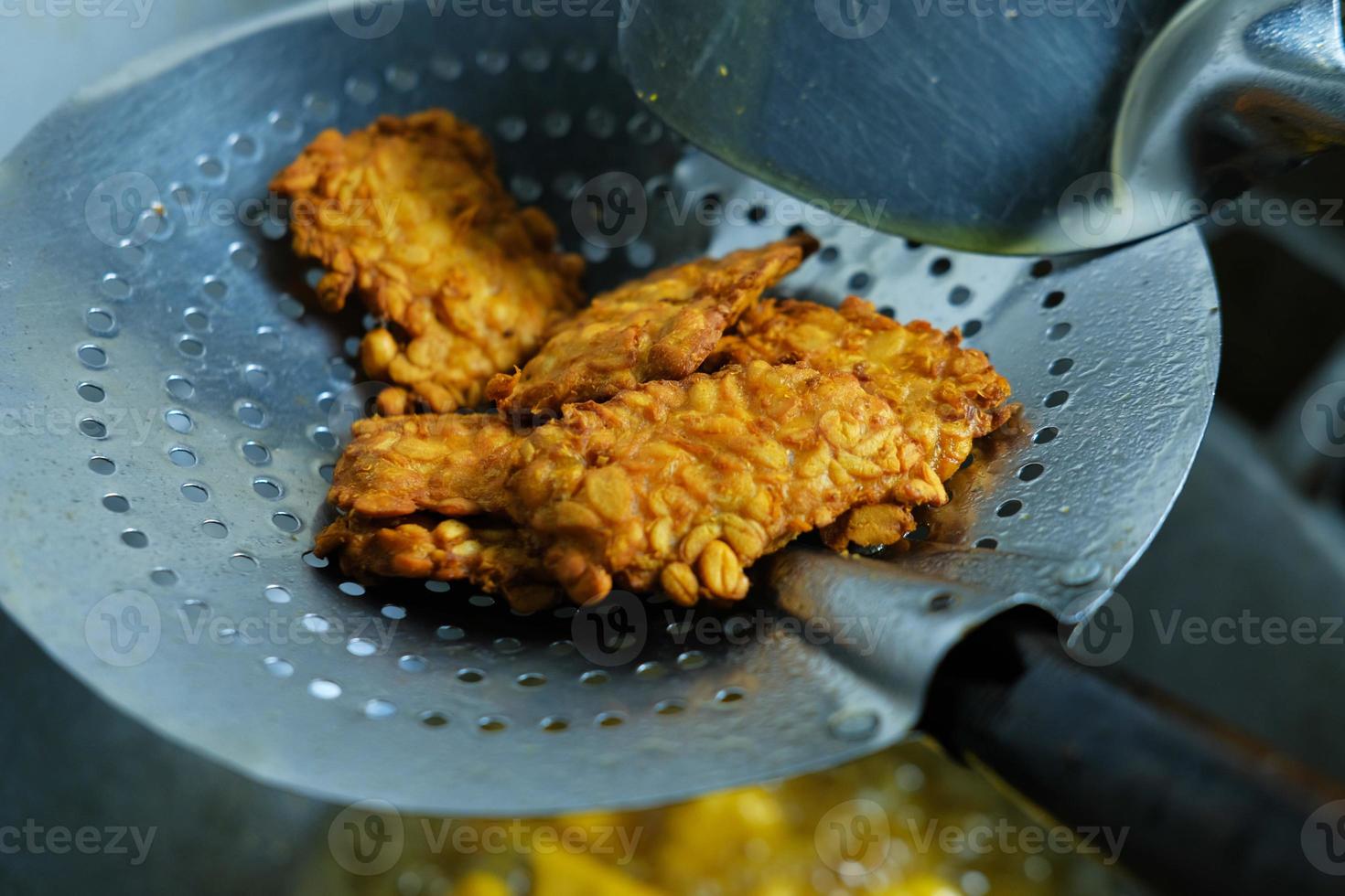 Traditional Indonesian food fried tempeh in a stainless steel sieve photo