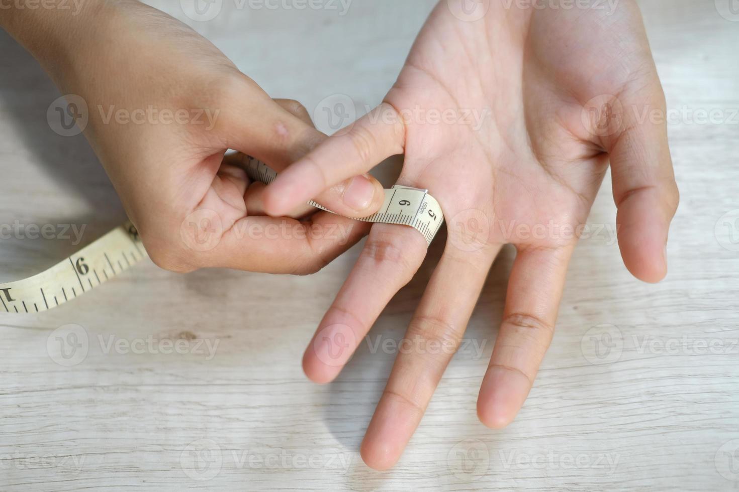 Female hand measuring finger with a tape measure photo