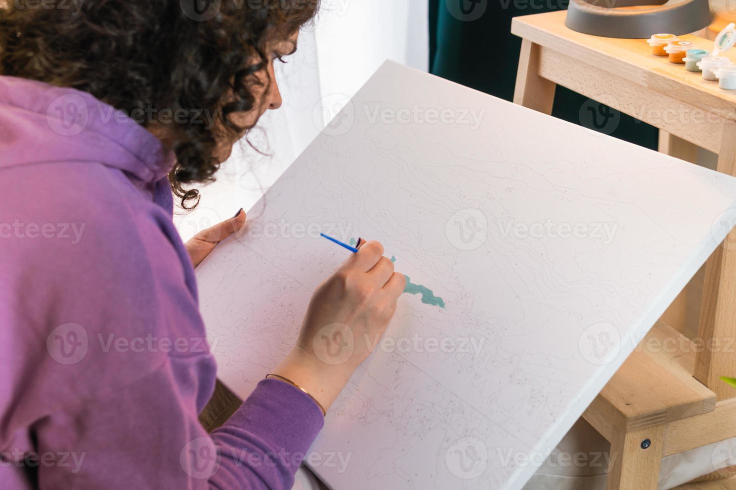 la mujer adulta pintando por números en el interior foto