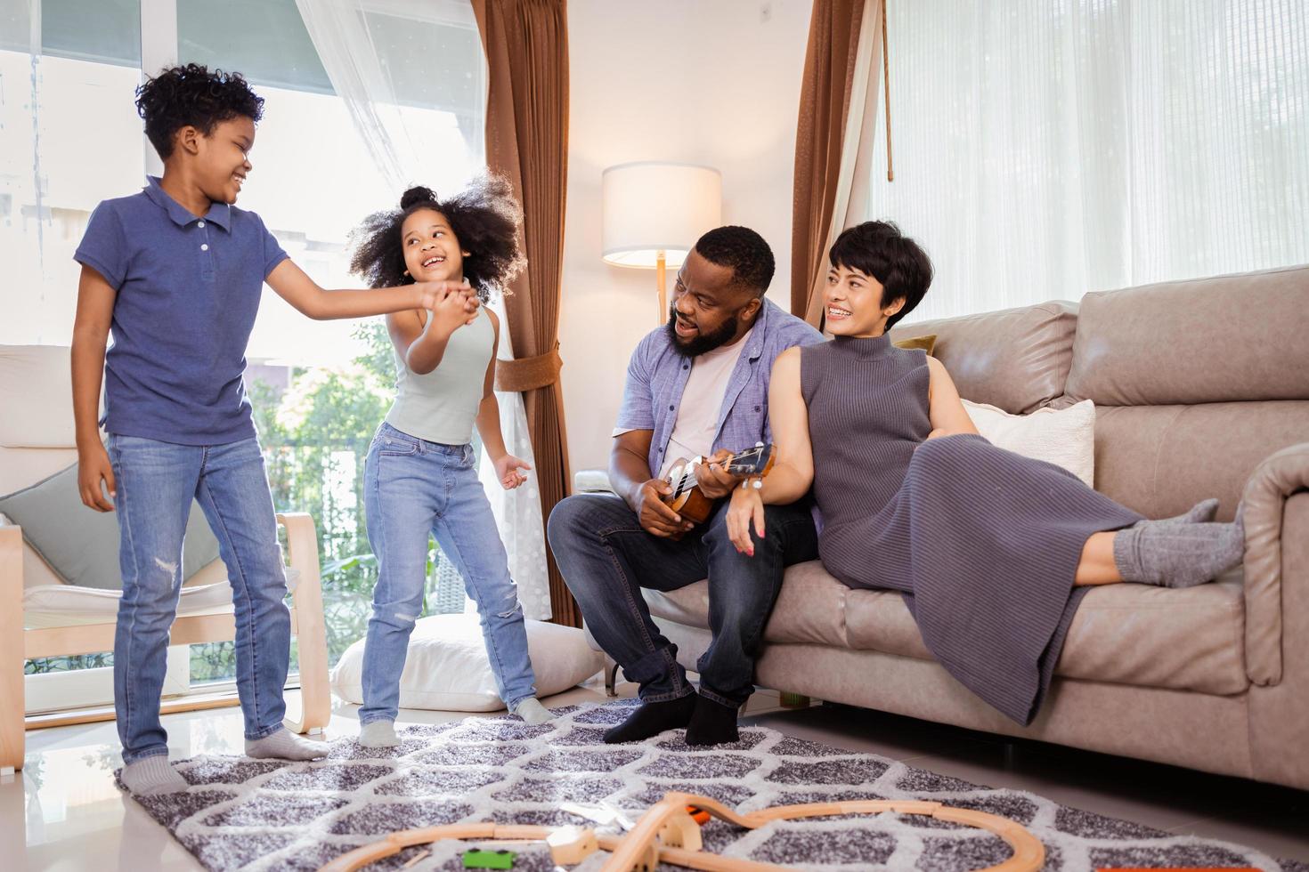 Happy African American family with little kids boy and girl dancing in the living room photo