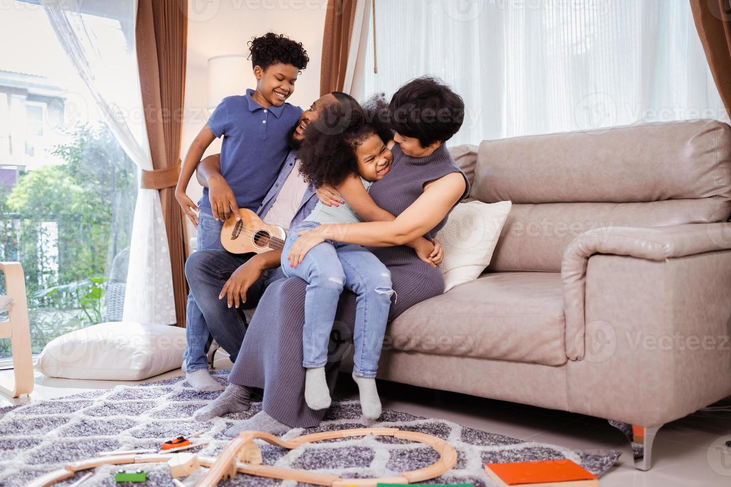 una familia afroamericana completa con niños pequeños, niños y niñas bailando en la sala de estar foto