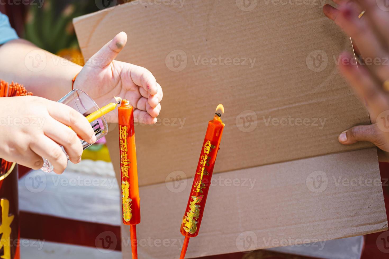 Closeup of person hands lighting red auspicious candle with golden Chinese on candlestick. photo