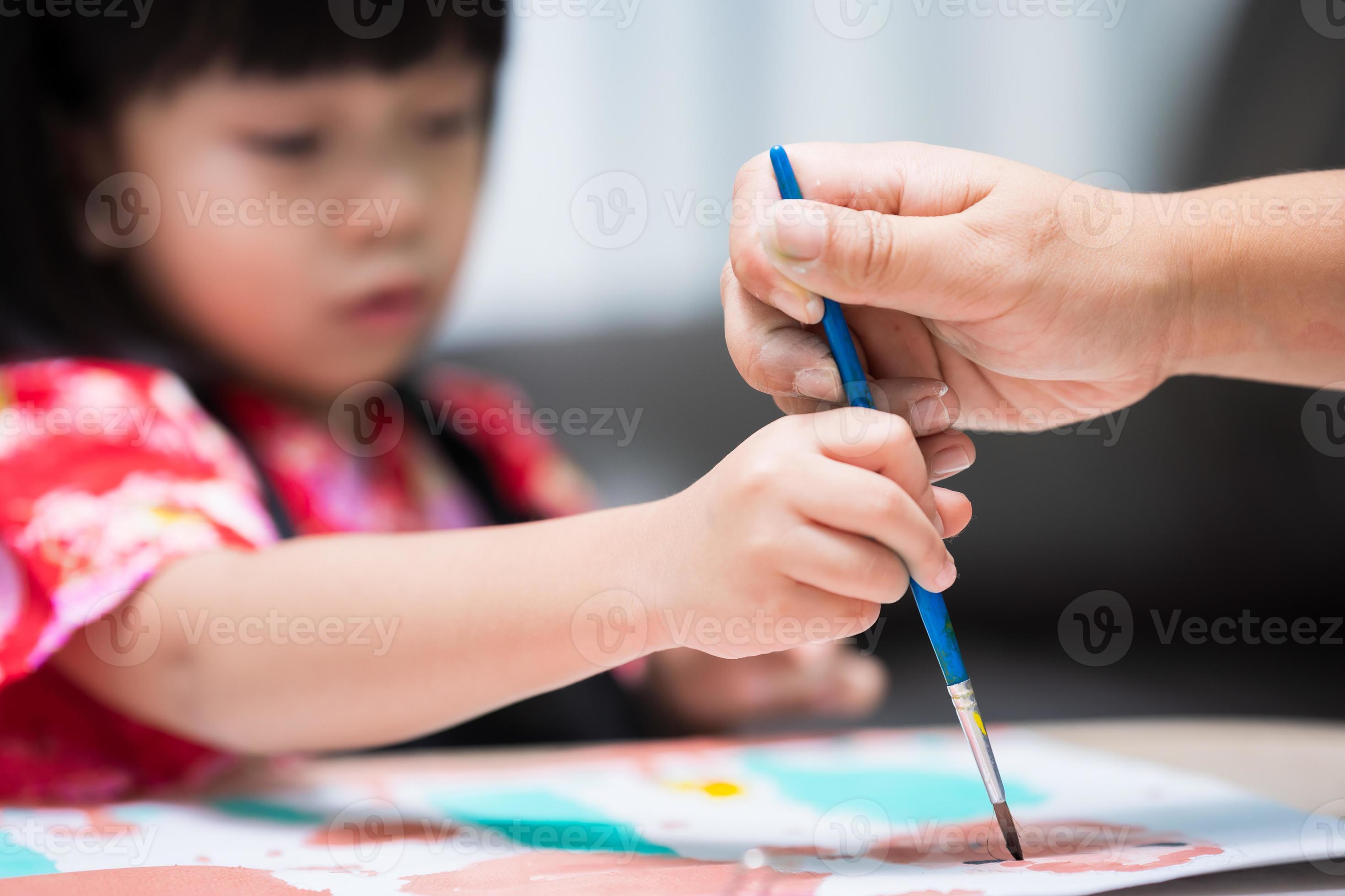 La mano de los niños con un pincel pinta una nube azul sobre una