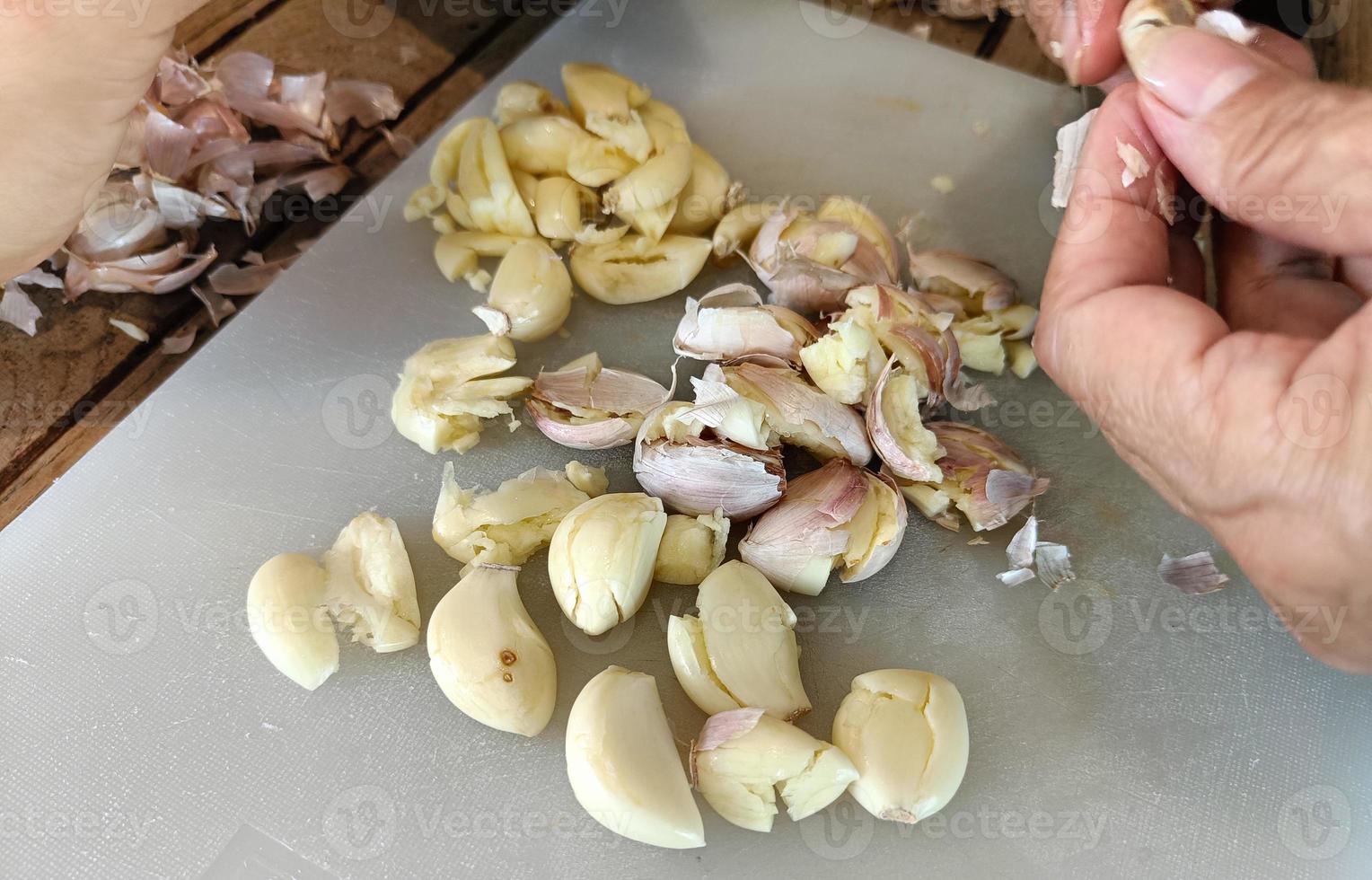 Woman peeling garlic on the cutting board for cooking photo