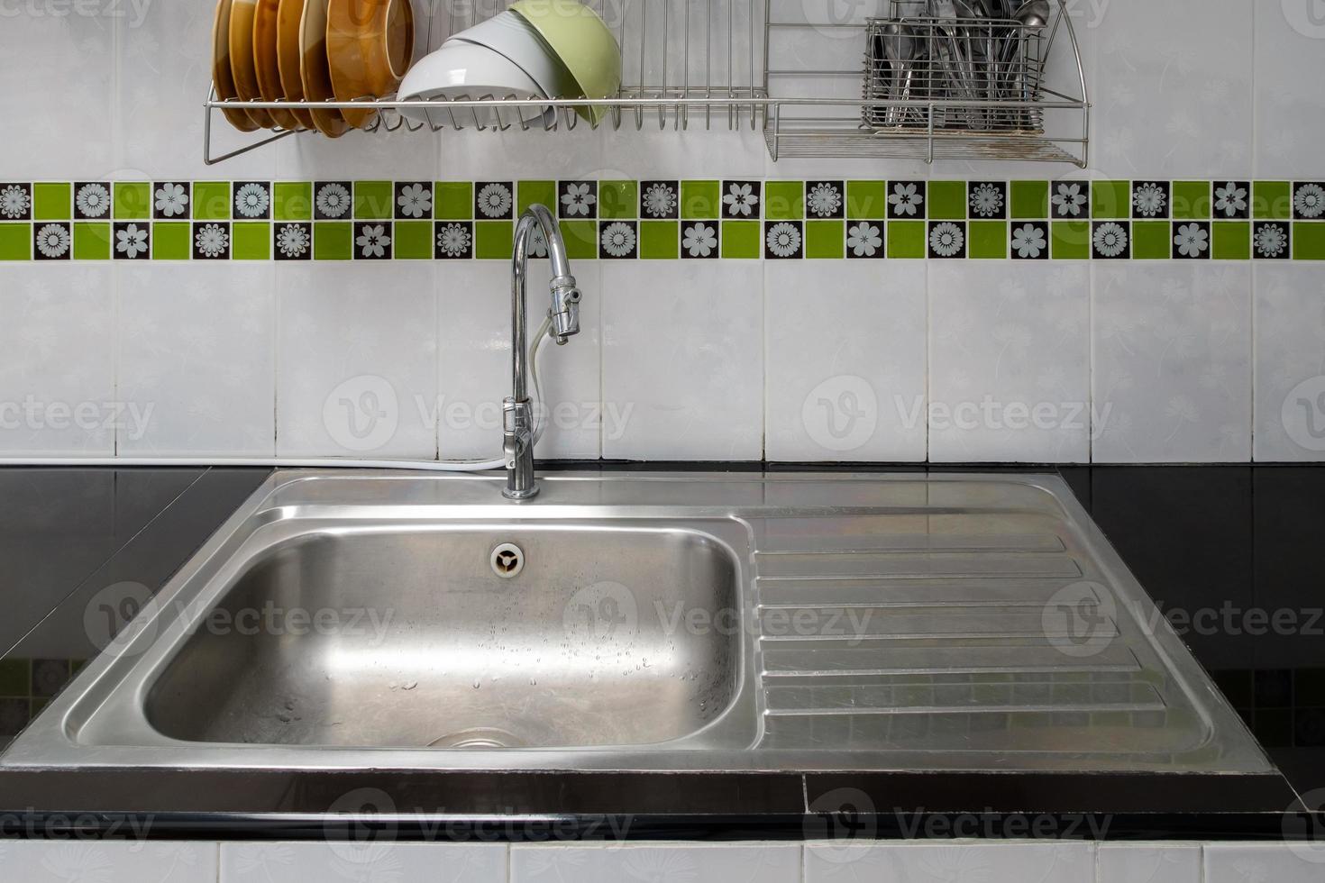 The modern sink on the black counter with the stainless steel rack. photo