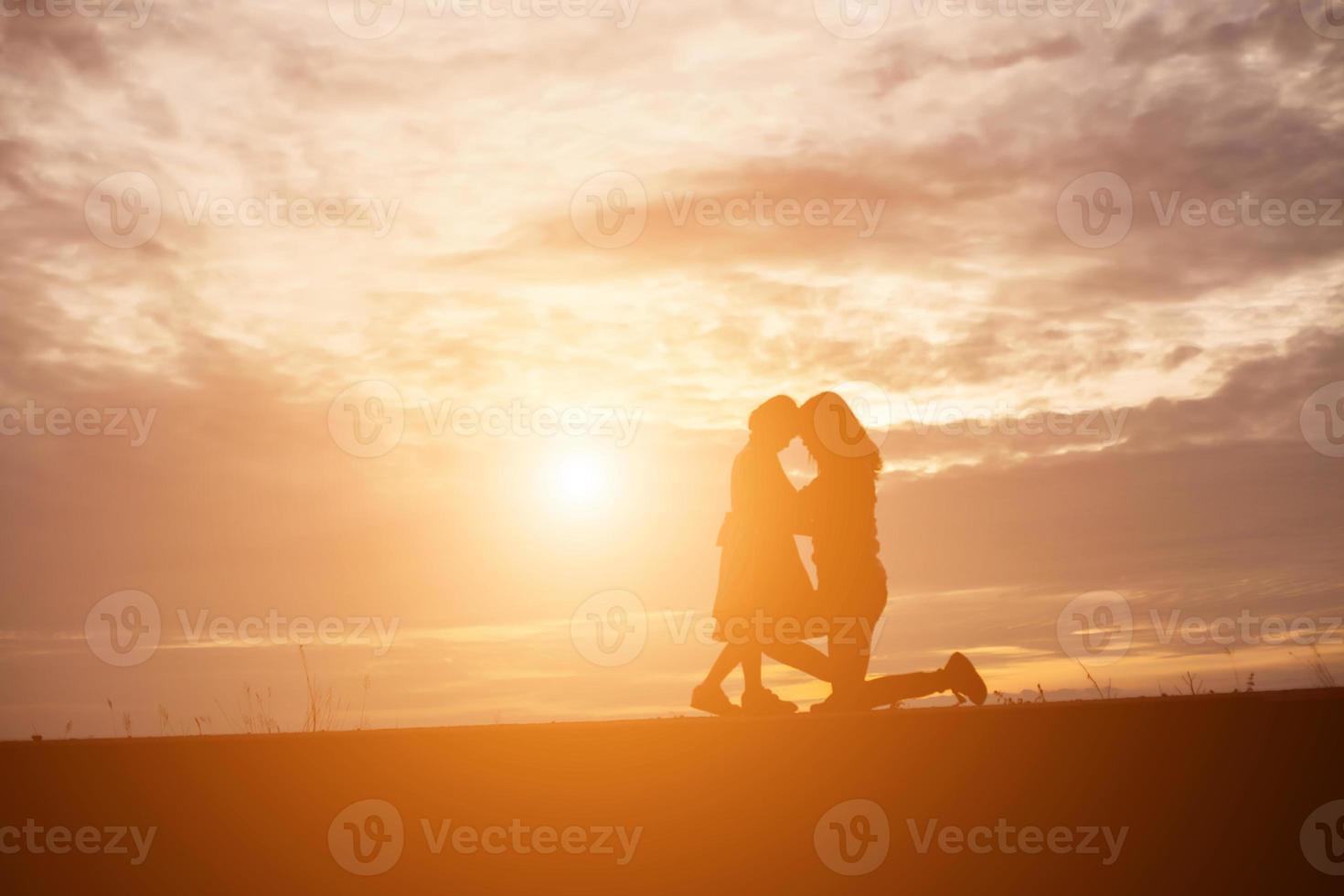 a silhouette of a happy young girl child the arms of his loving mother for a hug, in front of the sunset in the sky on a summer day. photo
