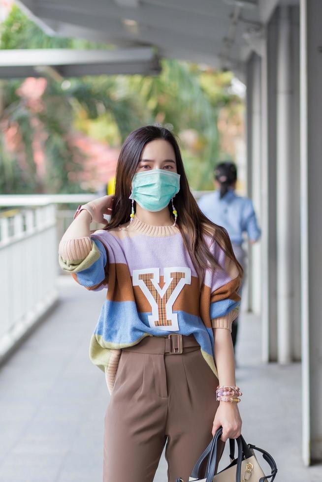 Beautiful Asian woman walking in the city wear Colorful sweaters, long hair and medical masks in a new normal  ,Pollution PM2.5 and health care concept. photo
