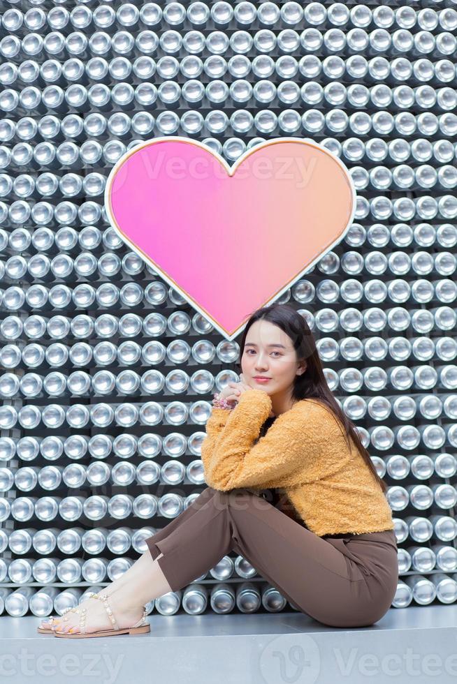 Asian beautiful woman with long hair is sitting and smiling in heart background as Valentine s day concept. abstract background photo