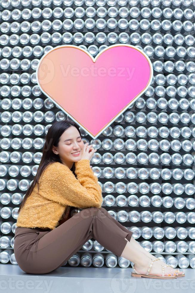 Asian beautiful woman with long hair is sitting and closing her eyes in heart background as Valentine s  day concept. abstract background photo