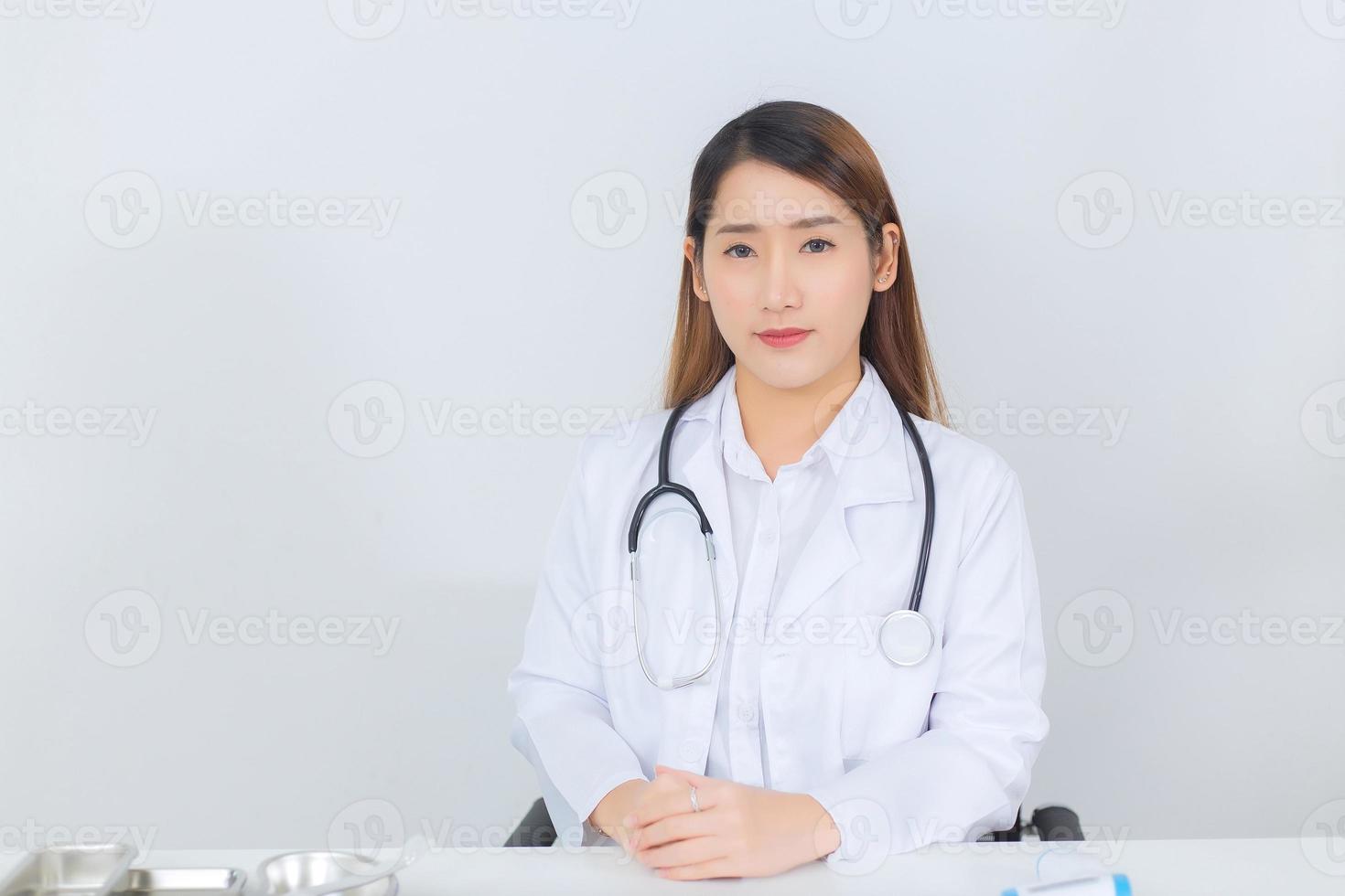 Asian professional  female doctor looking straight at the hospital wearing a white coat and a stethoscope On a white background Health care concept. photo