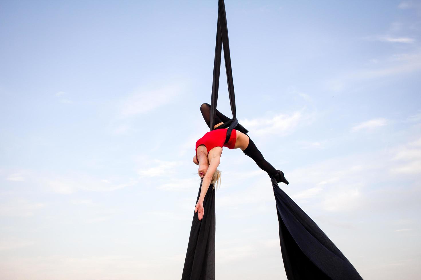 exercises with aerial silk outdoor, sky background. beautiful fit woman training acrobatic in airt. photo