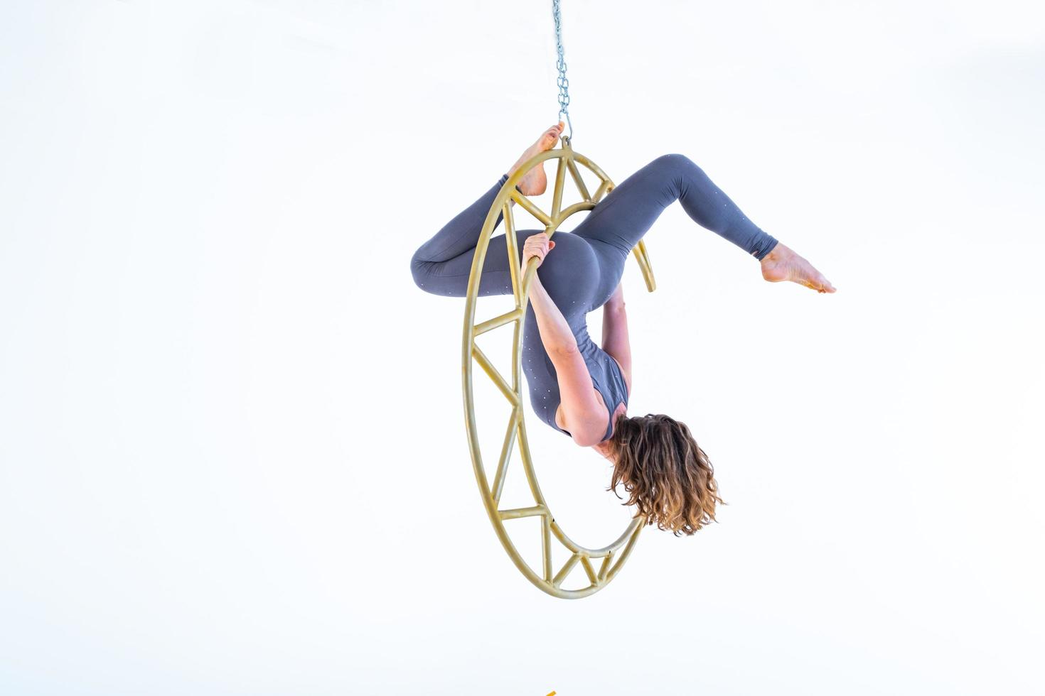 Woman hanging in aerial silk in white studio photo