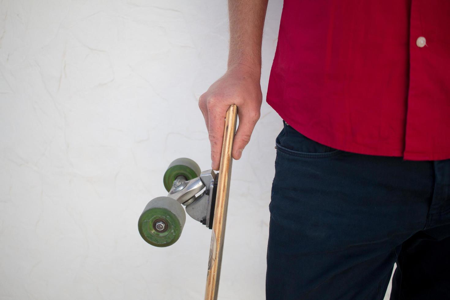 joven barbudo montando en patineta, hipster con longboard en camisa roja y blue jeans de fondo urbano foto