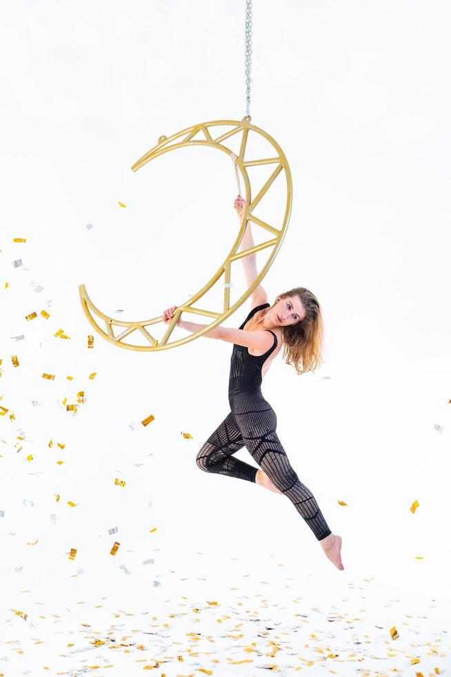 Woman hanging in aerial silk in white studio photo