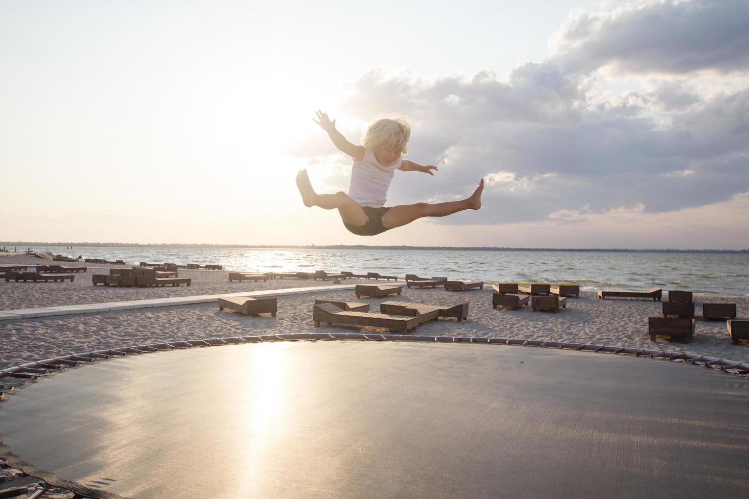 little girl jump and having good time on trampoline in summer time photo