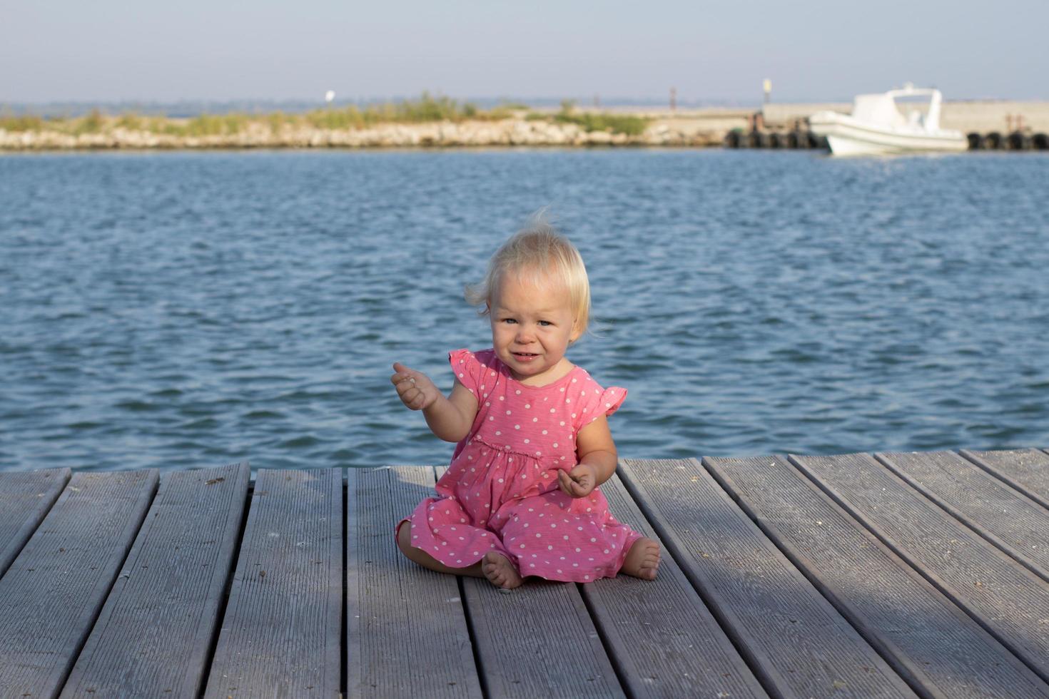 Little girl in pink dress near the river photo