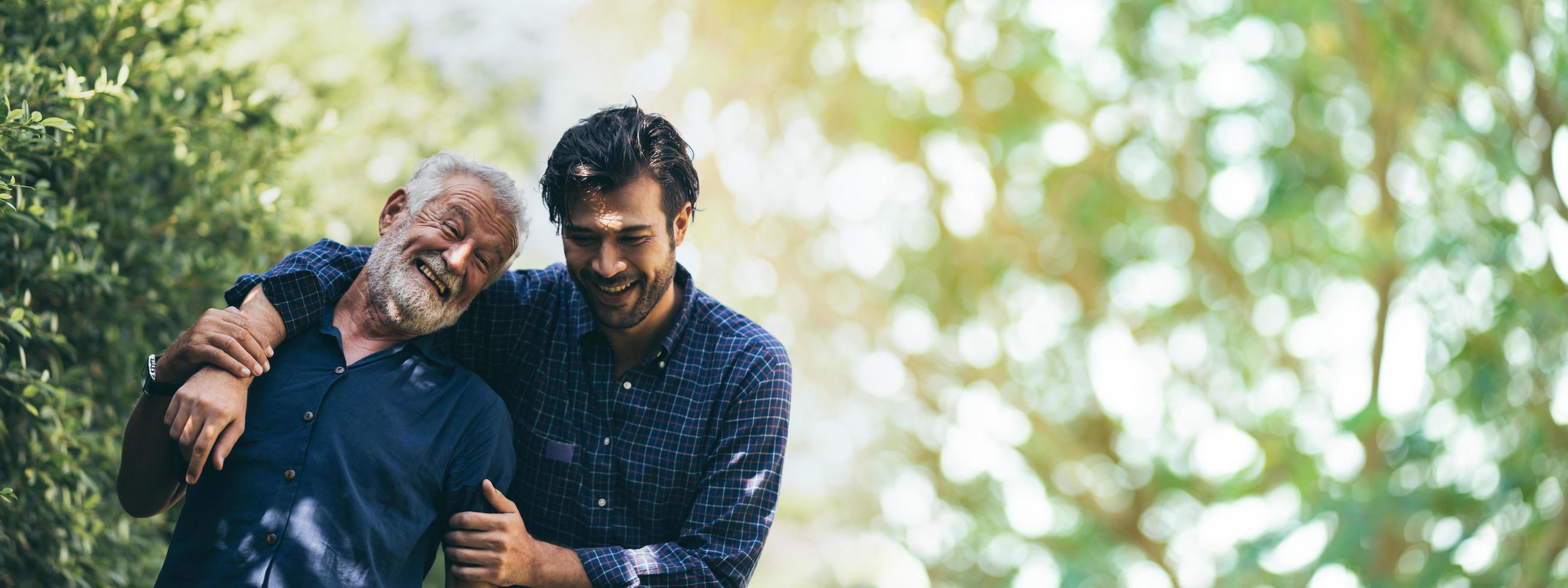 senior father hugging adult hipster son, have a happy feeling together, elderly caucasian person man or grandfather smiling with love in concept of family at home nature outdoor garden, banner space photo